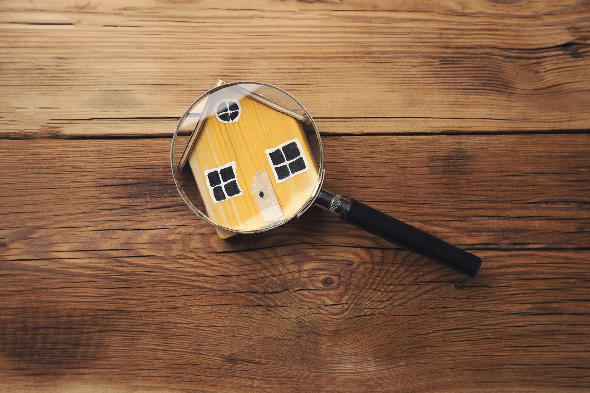 magnifying glass on a yellow miniature house