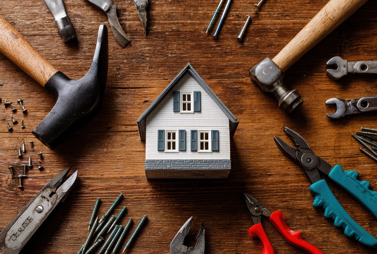 old miniature house surrounded by handyman tools